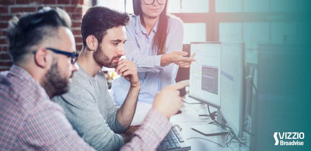 A imagem reflete 3 pessoas em volta de um computador. Título do artigo Consultoria de Outsourcing: Estratégia fundamental para sua empresa